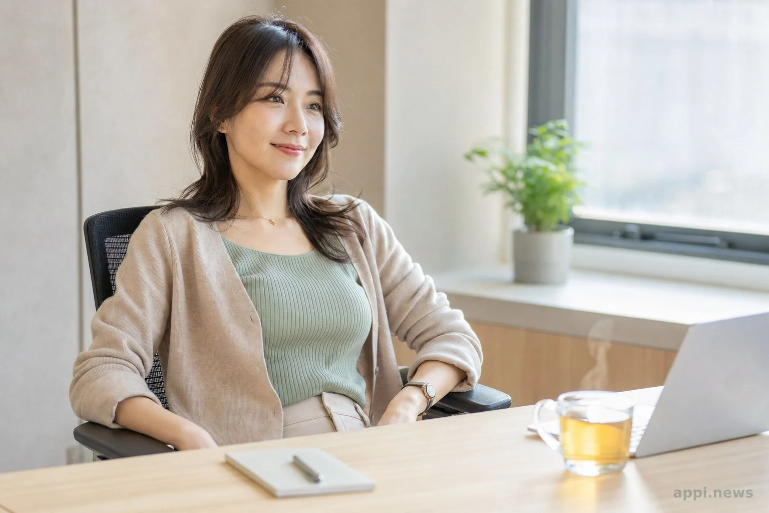 上班族女性在辦公桌前伸展腿部並喝穀物茶的情境照片