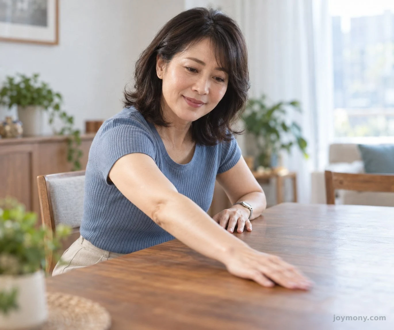 一位成人在家站於桌旁，輕柔活動手臂。